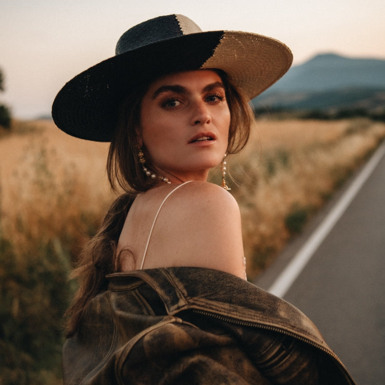 Woman wearing The Straw Iconic Limited Eclipse — a black and white duo-tone straw hat with a wide brim, a unique statement design from Old Habits Die Hard, perfect for summer hat styles and standout looks.