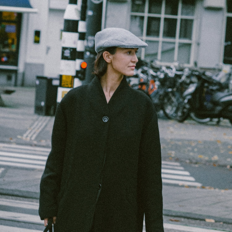 The Flat Cap Bit of Blue worn on a city stroll, a versatile unisex cap for all seasons. Blauwe platte pet gedragen tijdens een stadswandeling, perfect voor elk seizoen